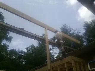 Carpenter setting a ridge beam over a new addition frame — Ice Dam Removal by Roofing Brothers in Stirum