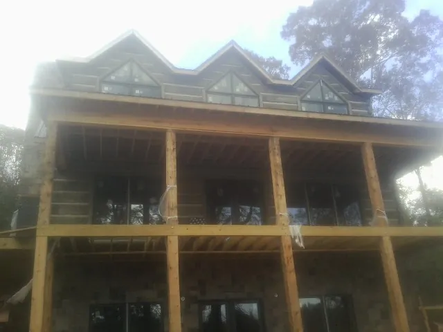 Dormers and porch framing on a large log home under construction — Roof Coating work by our crew in Stirum