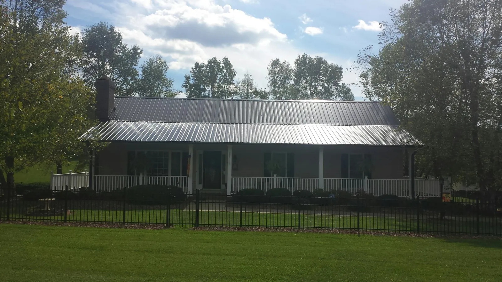Gray metal roof on a brick ranch with a full width front porch — Gutter Guard Installation work by our crew in Stirum