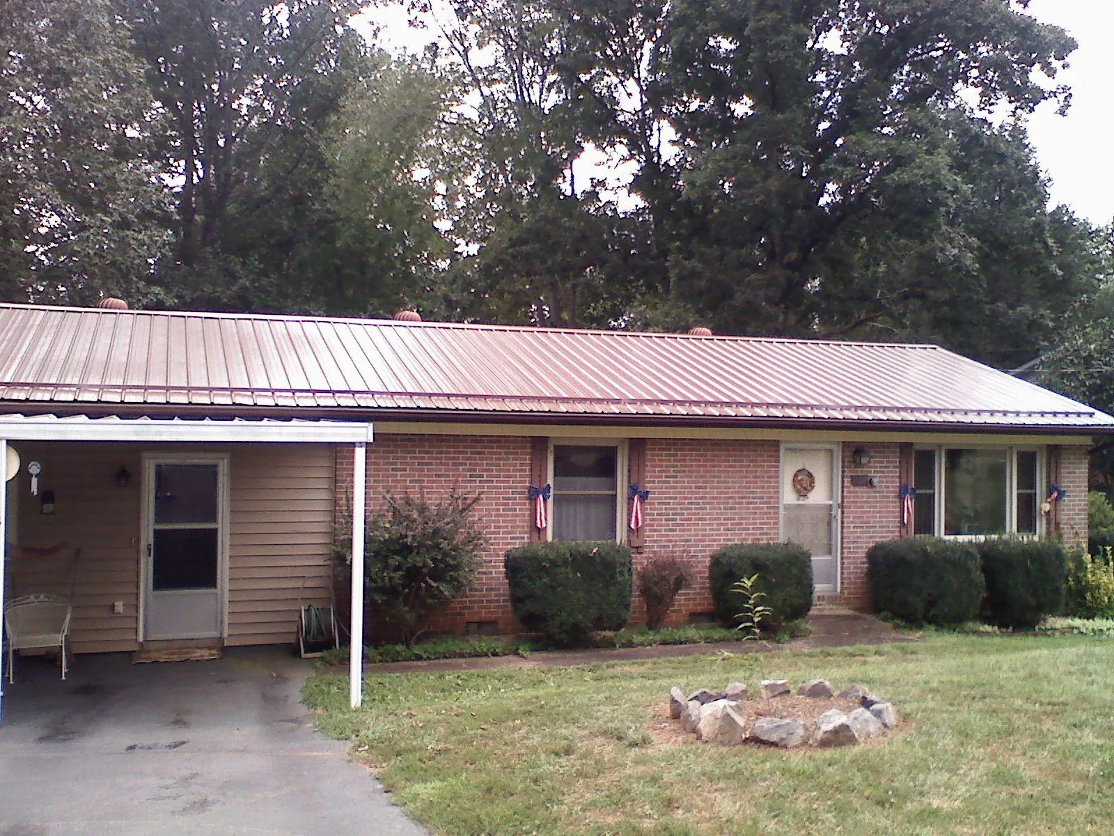 Bronze metal roof and carport on a brick ranch home — Roof Repair work by our crew in Stirum