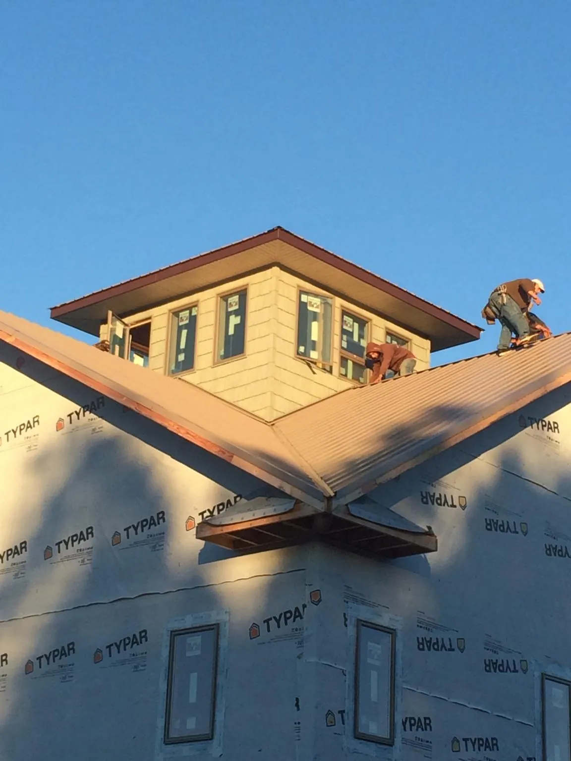 Roofers working around a rooftop cupola on a new metal roof at sunset — Roof Waterproofing in Stirum by Roofing Brothers